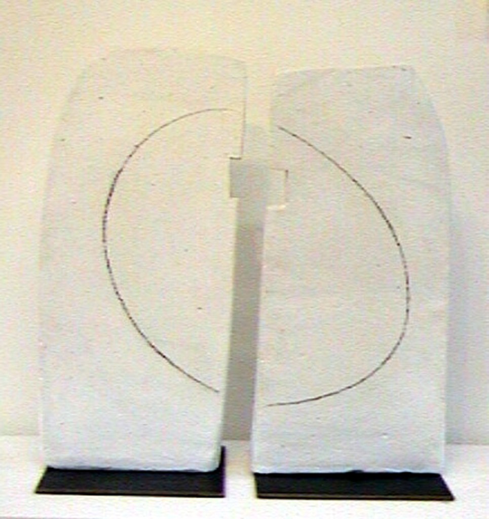 Ceramic clay sculpture in two rectangular parts, painted white with black circular line painted on both pieces.