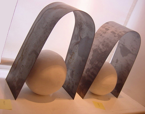 Two white clay spheres under two steel arches.