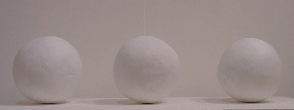 Three white spherical sculptures on a plinth with white background, by Ser James Irvine.